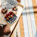 Top view of a healthy breakfast tray with fruits, bread, and juice on a striped tablecloth.
