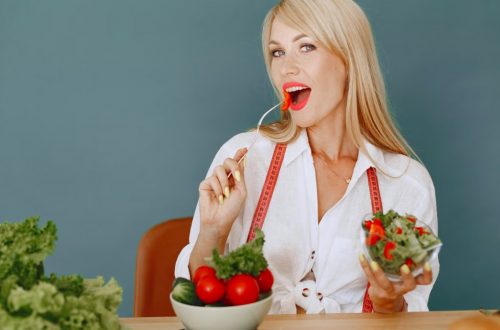 Woman enjoying a fresh salad with tomatoes and greens, promoting healthy eating.